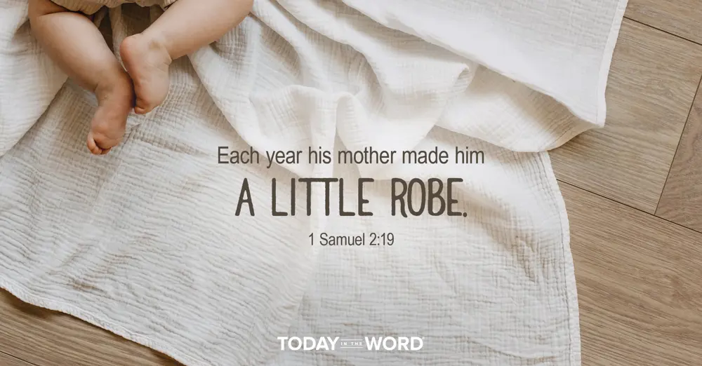 Today's daily devotional Bible verse: 1 Samuel 2:19 Each year his mother made him a little robe. | A baby crawling on a white linen blanket.