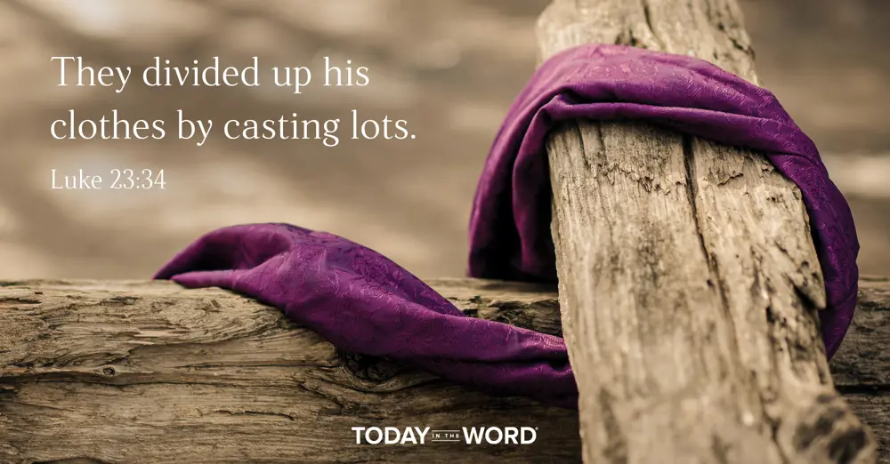 Today's daily devotional Bible verse: Luke 23:34 They divided up his clothes by casting lots. | A purple cloth draping wooden beams.